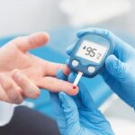 A high-quality, professional photograph focusing on blood sugar control, featuring a close-up of a healthcare provider's hands in blue clinical gloves performing a glucose test on an Indian patient's finger